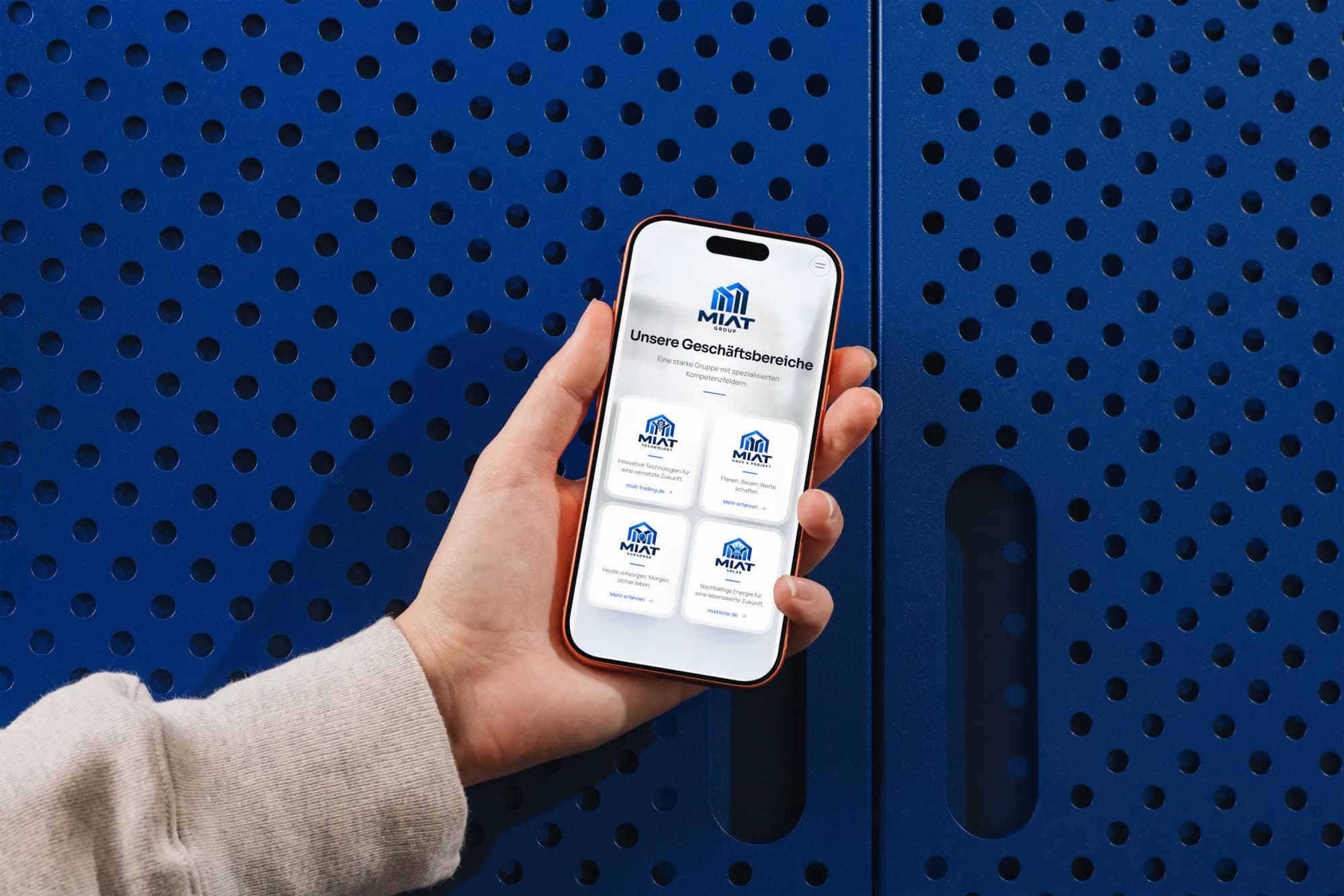 MIAT Group – Mobile Startseite mit vier Markenkarten auf iPhone in der Hand