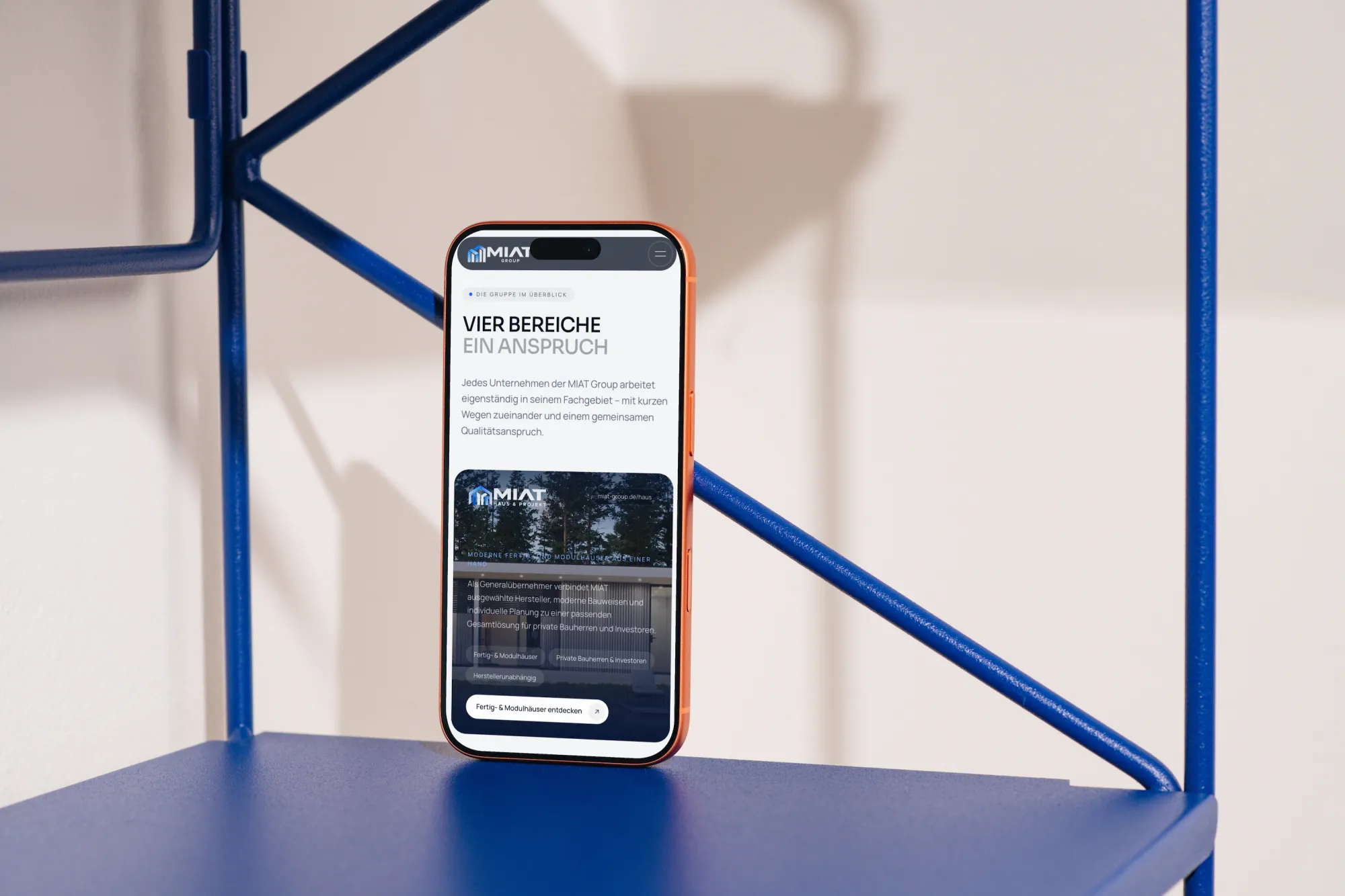MIAT Group – Übersicht „Vier Bereiche, ein Anspruch“ mit der Karte Haus & Projekt auf iPhone im Regal